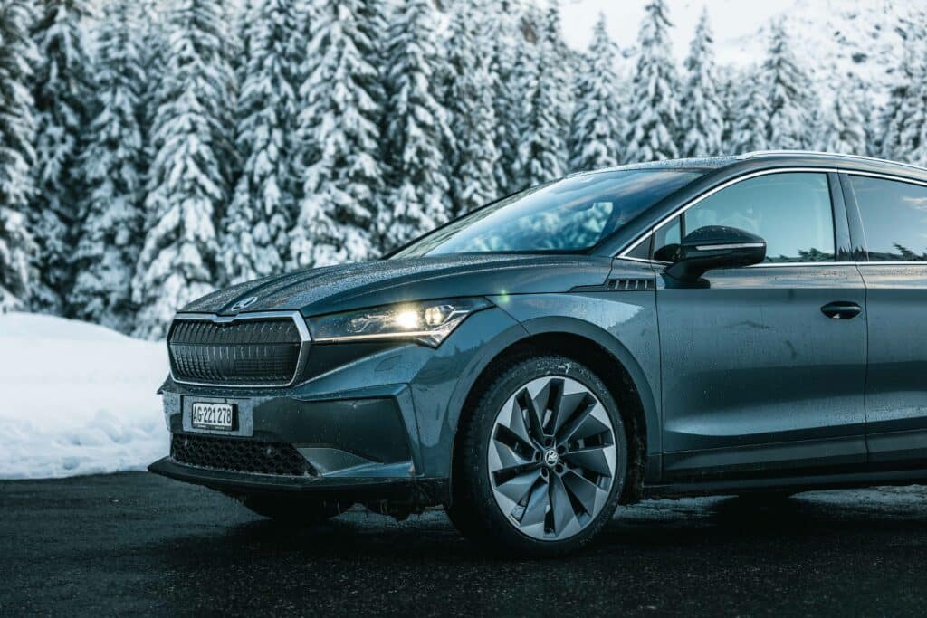 An electric car, the Skoda Enyaq, drives through a winter landscape with winter tires.